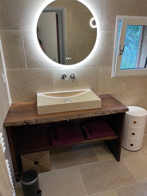 Helles Badezimmer mit Holzwaschtisch, großem Spiegel und moderner Einrichtung im La Combe de la Dame.