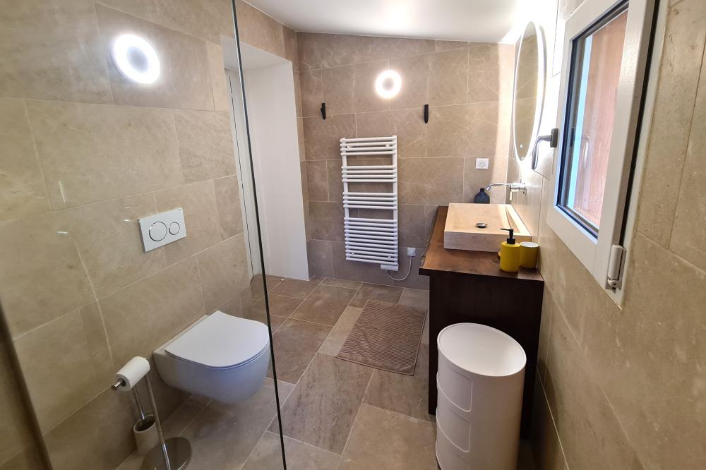 Alt: Helles Badezimmer mit Bad, WC, Waschbecken und Heizkörper in stilvollem Design.