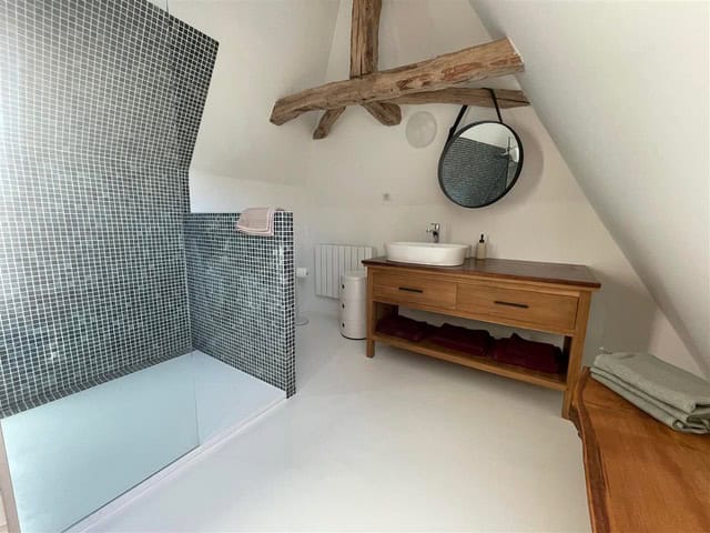 Modernes Badezimmer mit Holzwaschtisch, Spiegel und begehbarer Dusche, perfekt für einen erholsamen Aufenthalt.