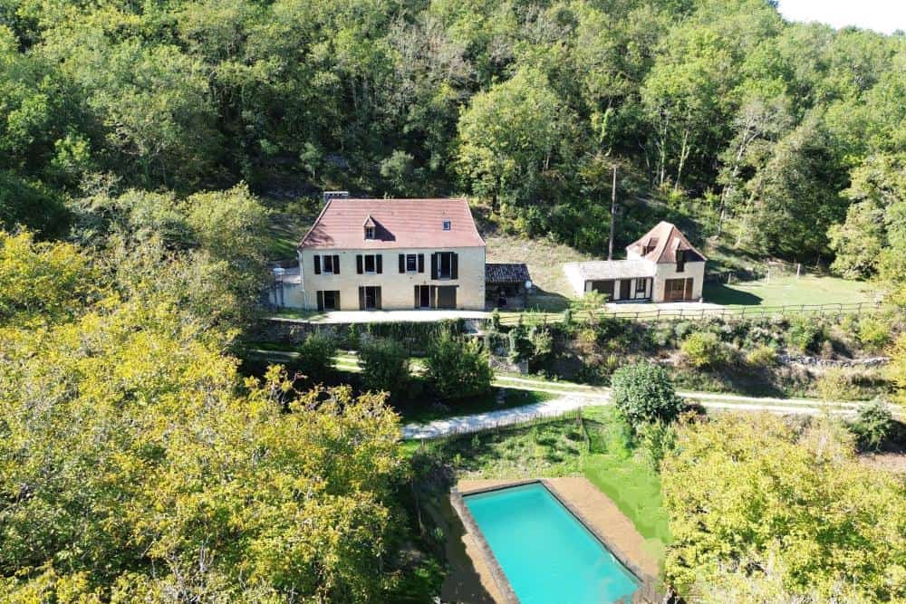 Vue aérienne d’une propriété en pierre du Périgord Noir avec piscine et dépendance dans la Vallée de la Dordogne