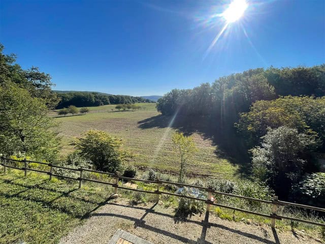 Landschaft mit Feldern und Bäumen bei Sonnenschein in der Combe de la Dame, perfekt für Natur- und Wanderliebhaber.