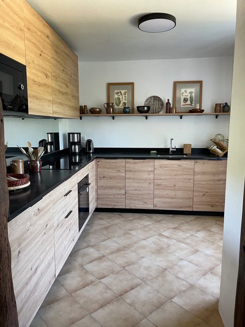 Helle, minimalistische Küche mit Holzschränken und schwarzen Arbeitsflächen in La Combe de la Dame.