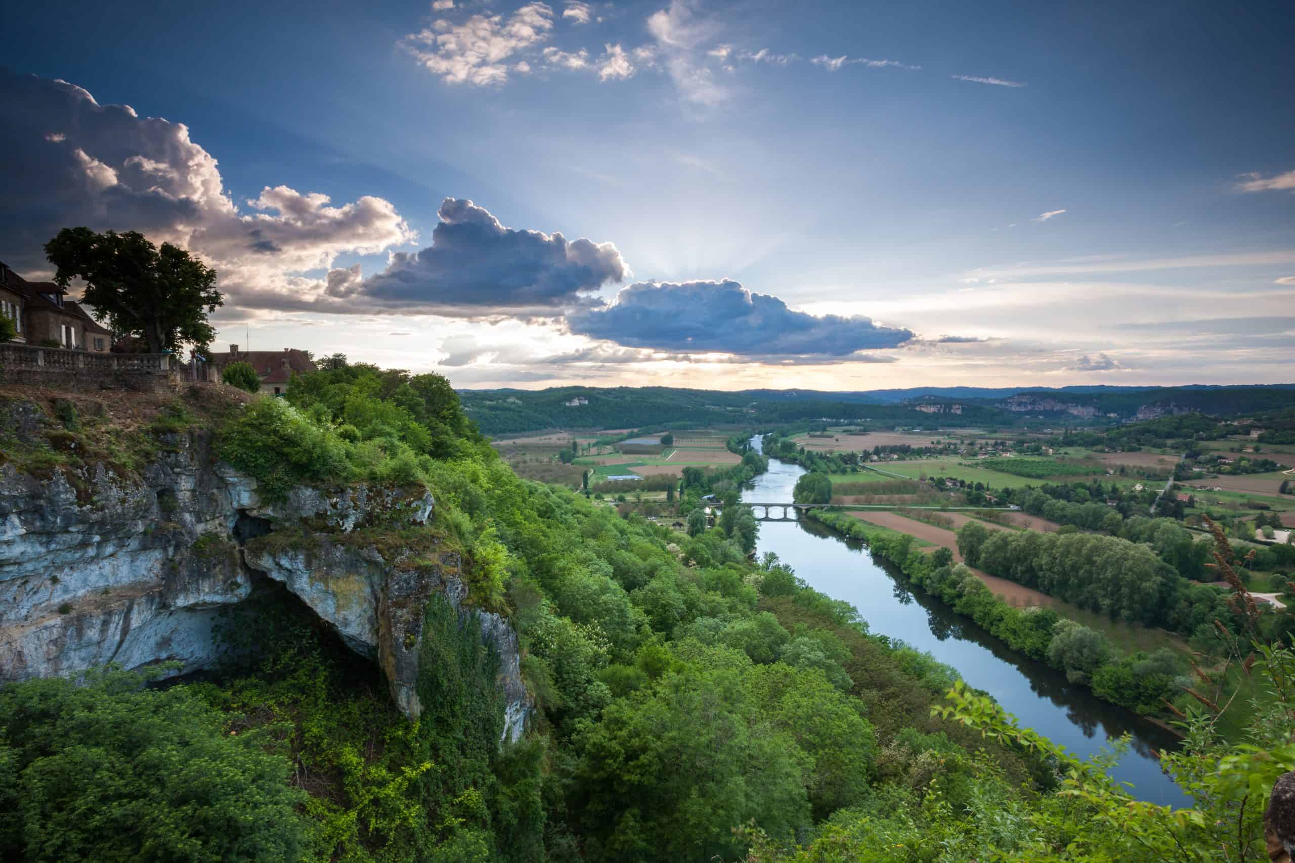 Aussicht auf die Combe de la Dame mit Fluss, grünen Hügeln und Himmel bei Sonnenuntergang.